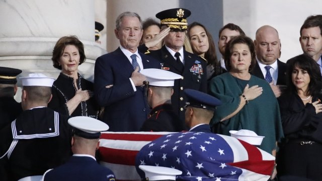 Former President George W. Bush and his wife Laura watch as his father's casket is carried into the U.S. Capitol