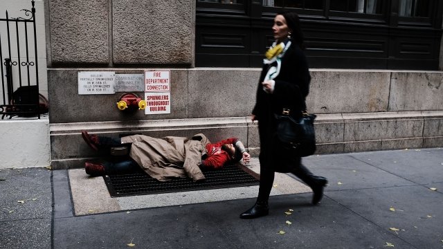 A woman walks by a homeless man.