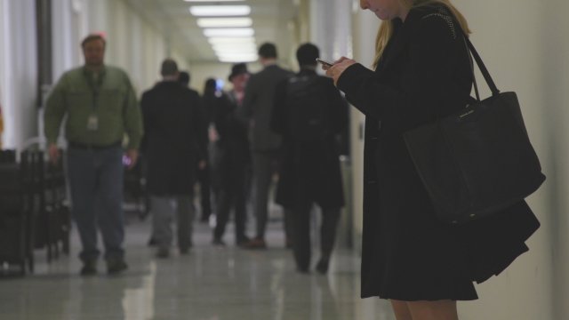 Woman checks phone in congressional hallway.