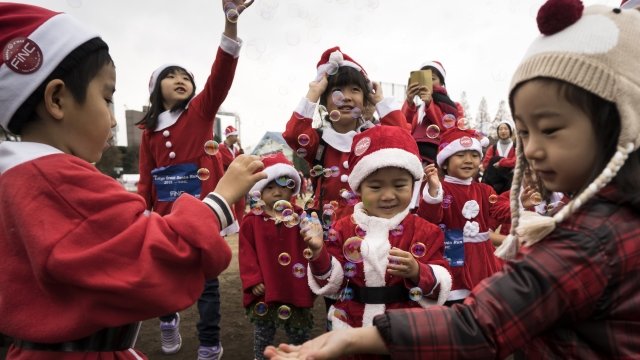 Children wearing Santa Claus costumes play with soap bubbles
