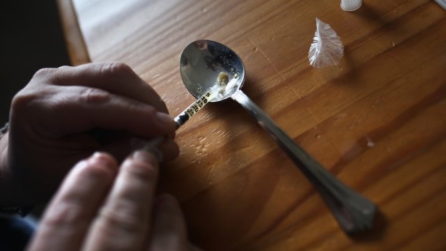 A person fills a syringe with heroin