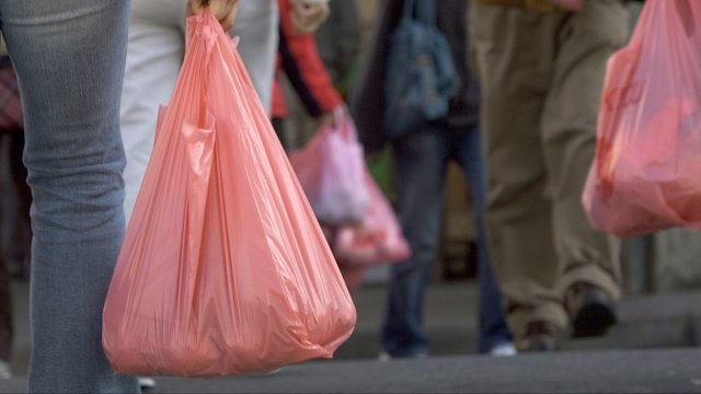 Shoppers carry plastic bags down the street
