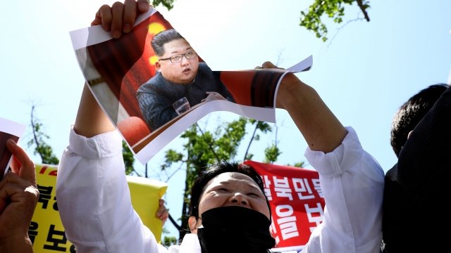 A North Korean Defector tears an image of leader Kim Jong Un