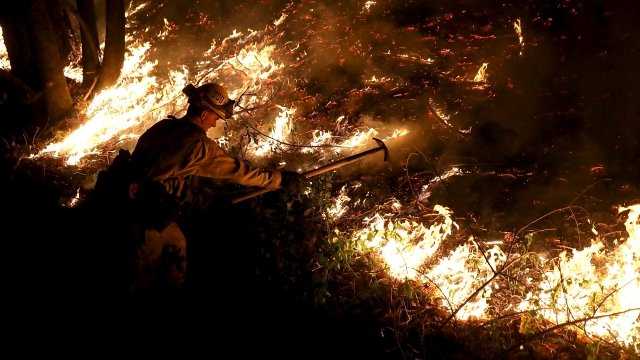 A CalFire firefighter uses a hand tool as he monitors a firing operation while battling the Tubbs Fire.