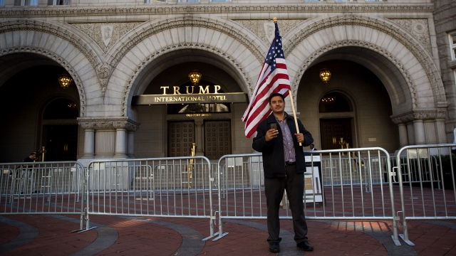 A man holds an American flag outside Trump International Hotel