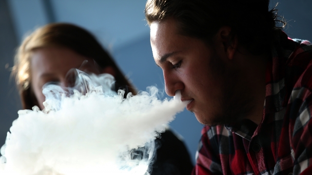 A man exhales a plume of e-cigarette smoke