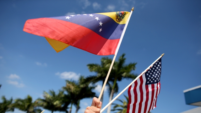 A person holding both a Venezuelan and an American flag