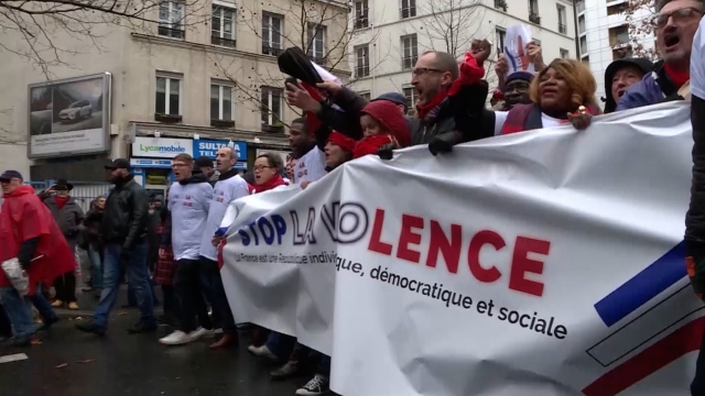 'Red scarves' hold up a sign in Paris that says, "Stop the violence."