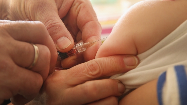 A doctor injects a vaccine against measles, rubella, mumps and chicken pox to an infant.
