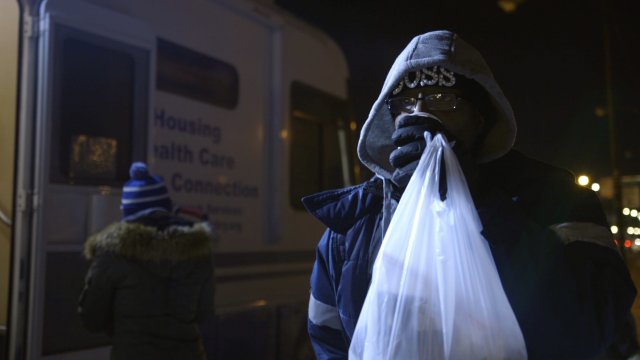 A man on the South Side of Chicago receives coffee and clothes from The Night Ministry outreach bus