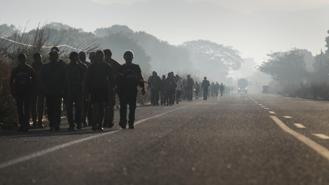 People from a caravan of Central American migrants walk alongside a highway.