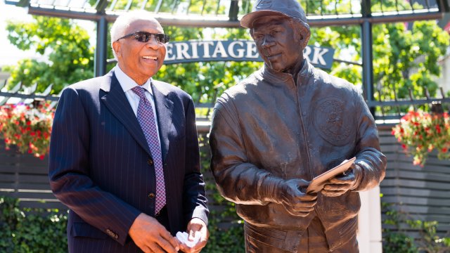 Frank Robinson stands with a statue commemorating his career prior to a Cleveland Indians-Kansas City Royals game.