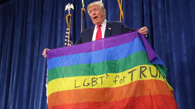 President Donald Trump holds an LGBT rainbow flag