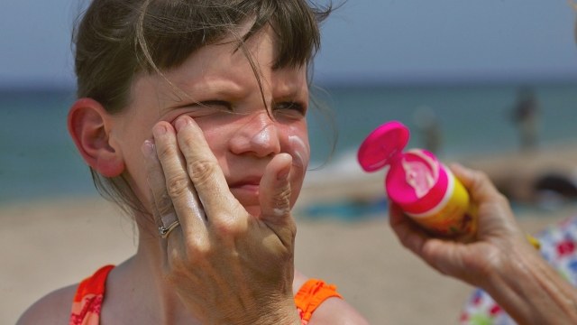 A woman puts sunscreen on a girl's face.