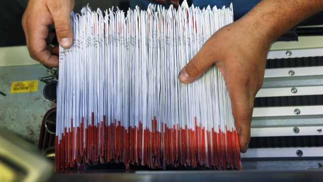 A man sorts through mail-in ballots.