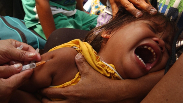 A young child cries as she is immunized with a measles shot.