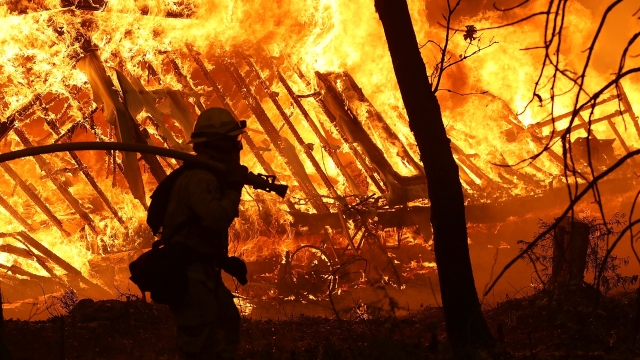 A Cal Fire firefighter monitors a burning home as the Camp Fire moves through the area.
