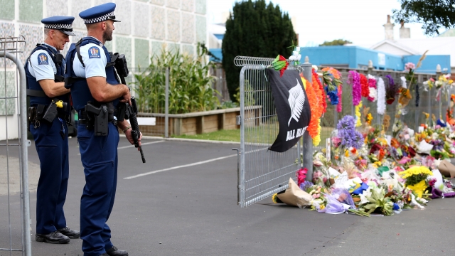 Police look on as locals lay flowers and condolences at the Huda Mosque in tribute to those killed and injured.