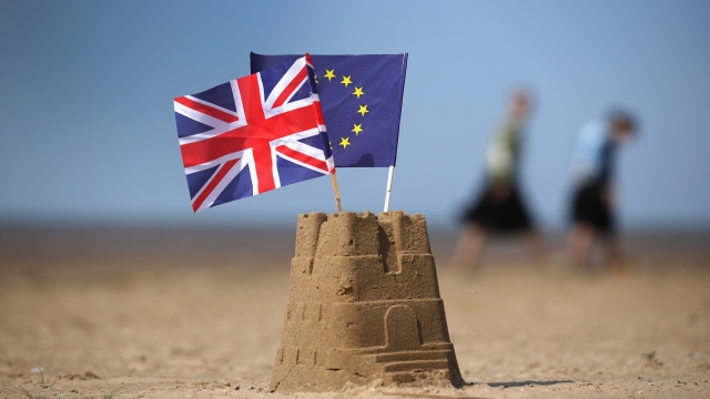 A sandcastle with the flags of the European Union and the U.K. on top