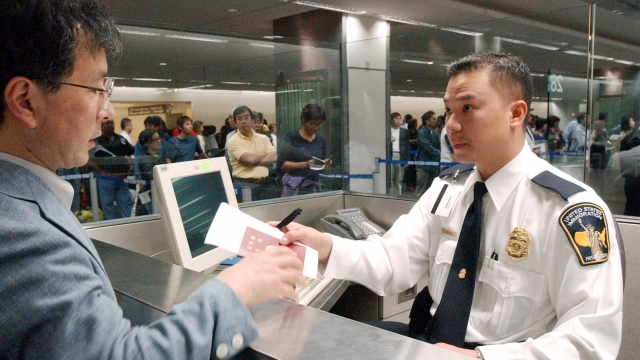 An immigration inspector processes a man going through customs