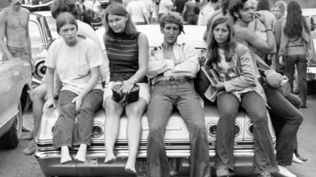 Teens sitting on car during 1969 Woodstock music festival