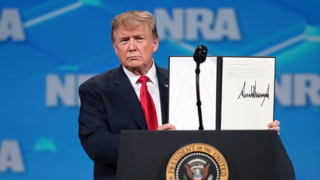 President Donald Trump holds up a signed document a the NRA Annual meeting