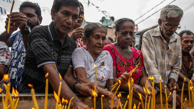 Mourners light candles for victims a week after Easter Sunday bombings in Sri Lanka.