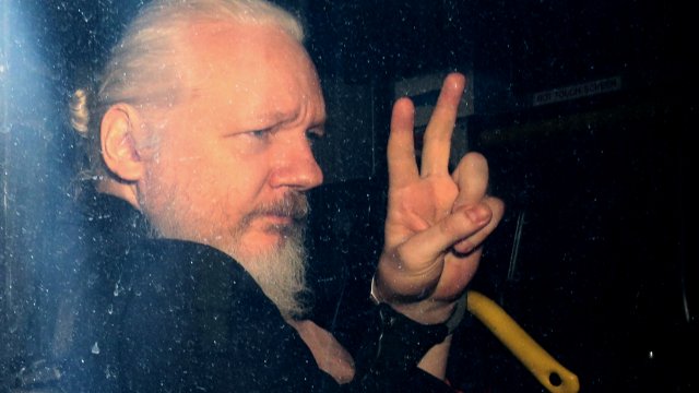 Julian Assange gestures to the media from a police vehicle on his arrival at Westminster Magistrates court on April 11, 2019