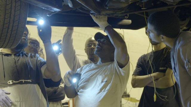 An instructor and students at Excel Automotive Institute