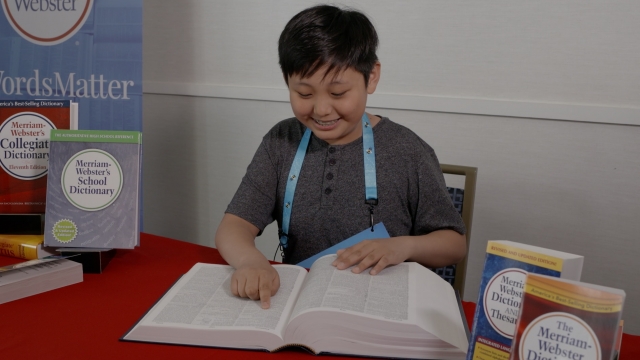 A Scripps Spelling Bee competitor looks up his favorite word in the dictionary