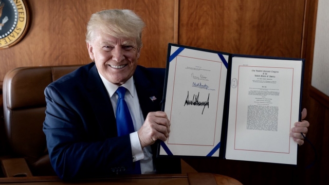 President Donald Trump holds signed bill