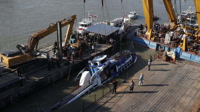 Crews lift the wreckage of a sightseeing boat out of the Danube River