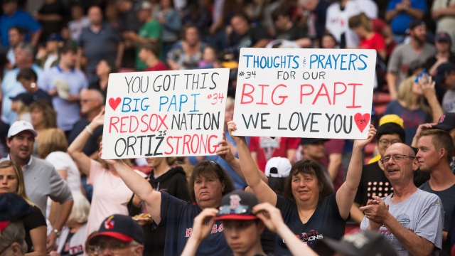 Fans hold up signs showing support for former Red Sox player David Ortiz