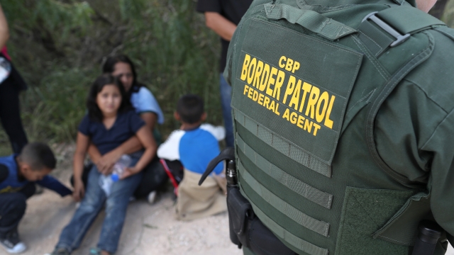 Central American asylum seekers wait as U.S. Border Patrol agents take them into custody.
