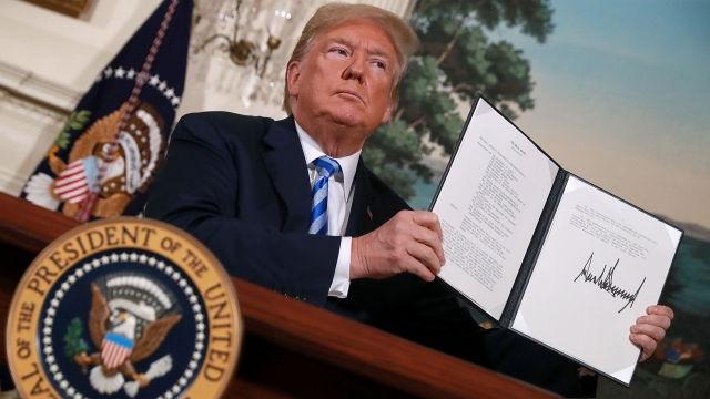 President Donald Trump holds up a memorandum that reinstates sanctions on Iran