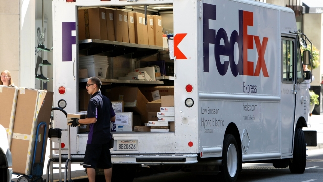 A FedEx worker unloads packages from his delivery truck.