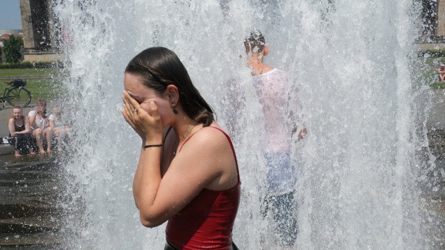 Young people cool off in a fountain in Lustgarten park during sweltering heat in Germany.