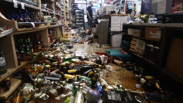 An employee stands at the register as broken bottles are scattered on the floor in Eastridge Market