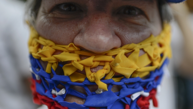A Venezuelan wears ribbons of Venezuelan colors to cover her mouth in a demonstration.