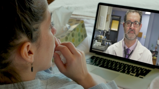 A woman video conferences with a doctor.