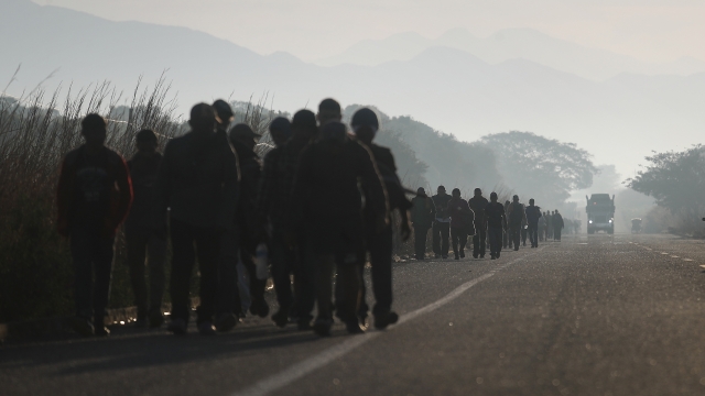 People from a caravan of Central American migrants walk alongside a highway.