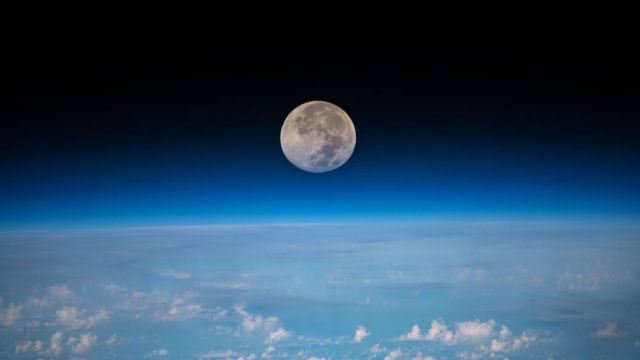The moon is pictured as the International Space Station orbits above the ocean
