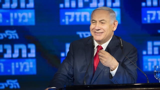 Prime Minister Benjamin Netanyhau smiles behind a podium.