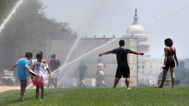 People cool off at open sprinklers on the National Mall, on July 19, 2019 in Washington, DC