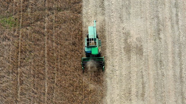 A farmer drives a John Deere Harvester.
