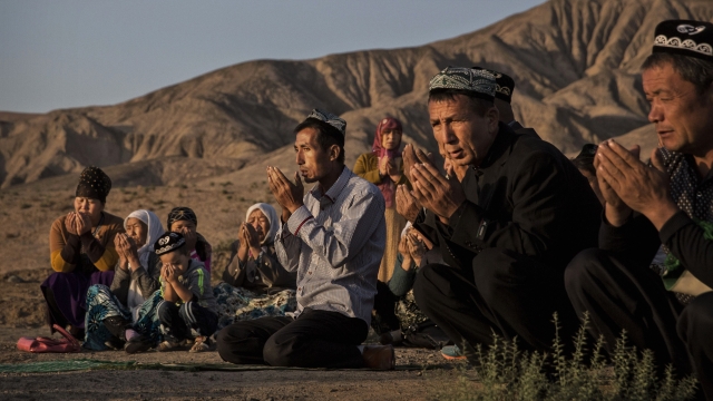 A Uyghur family kneels to pray at a local shrine in Xinjiang province, China