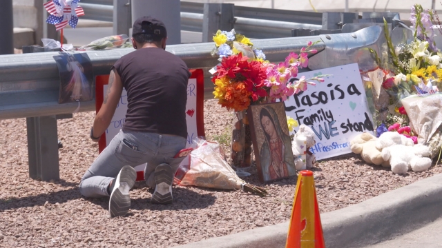 A person kneels next to a memorial for victims of the El Paso shooting.