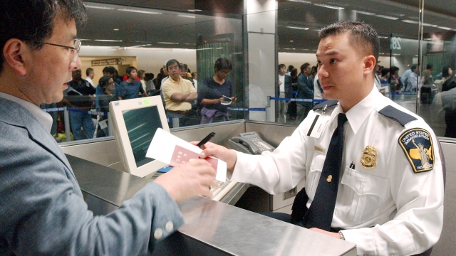 An immigration inspector processes a man going through U.S. customs