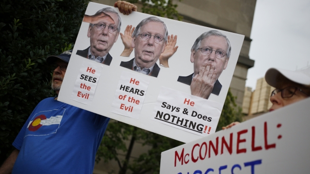 Activists hold signs while demonstrating outside the office of Senate Majority Leader Mitch McConnell