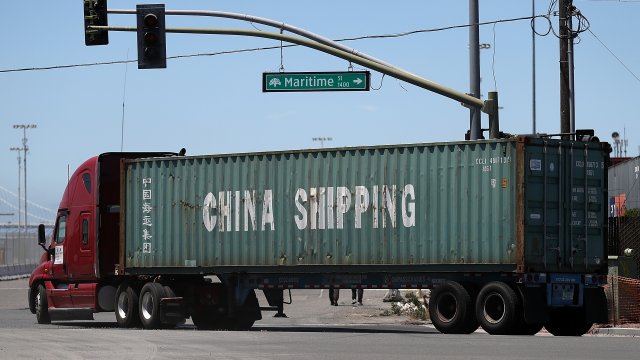 A truck carries a shipping container from China Shipping.